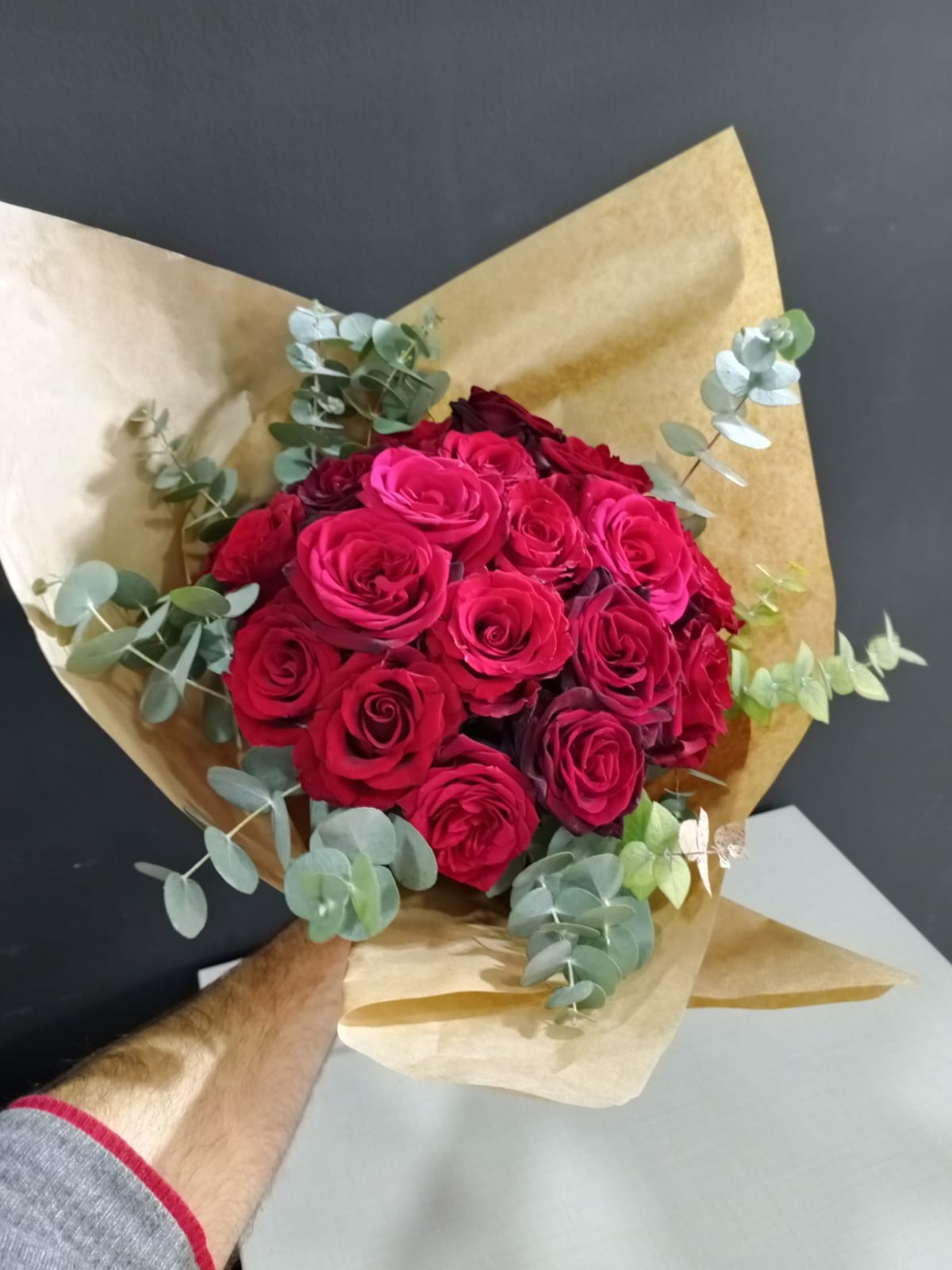 Dozen red roses with eucalyptus leaves wrapped in brown kraft paper
